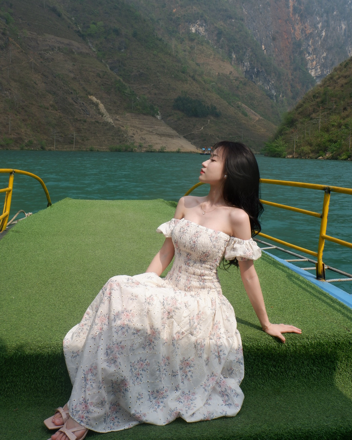 Mái tóc đen buông xõa, làn da trắng mịn cùng thần thái dịu dàng giúp cô nàng nổi bật giữa nền trời xanh biếc và dòng sông trong veo, tạo nên một bức tranh đẹp tựa cổ tích.