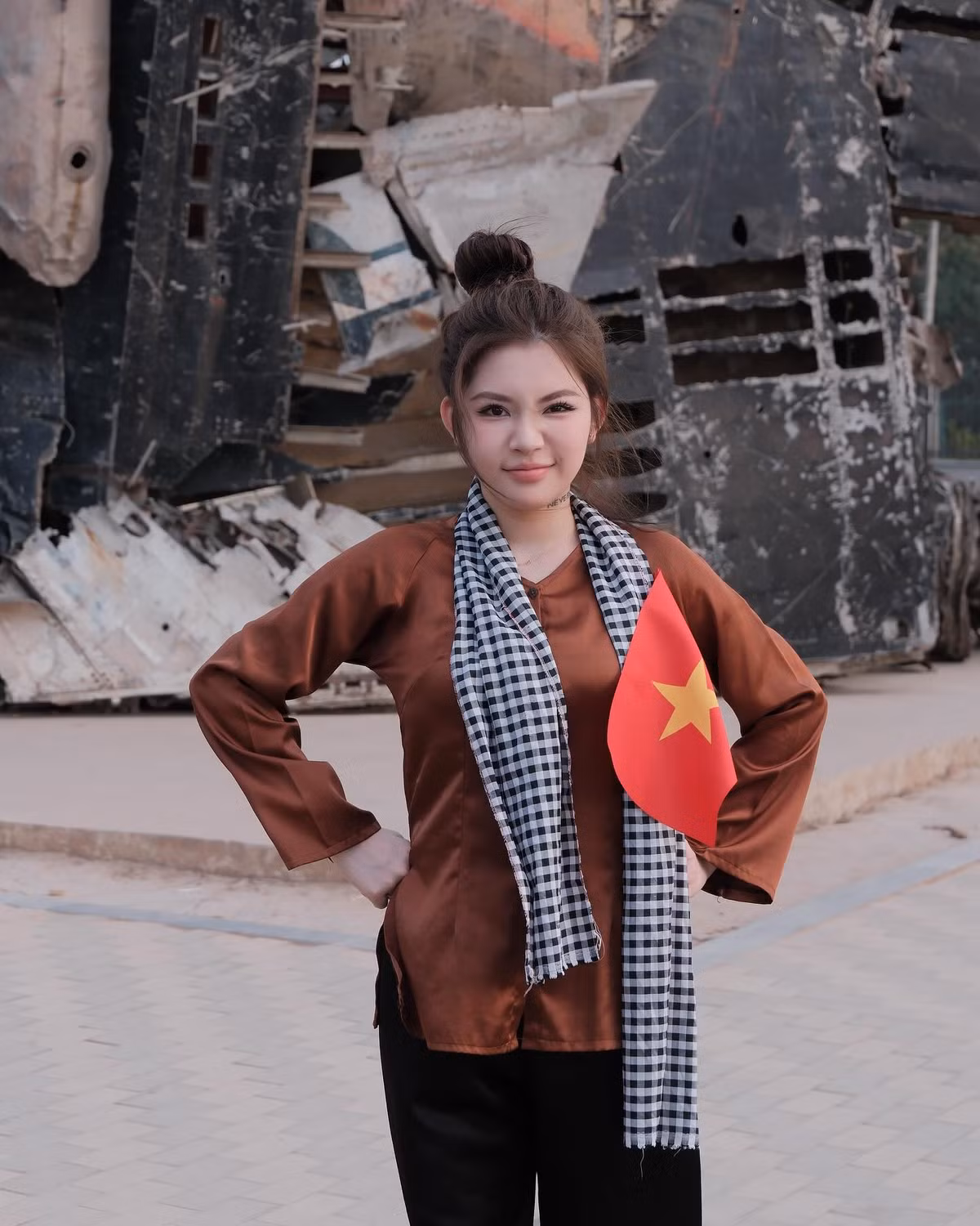 Trong một bối cảnh khác, Ngân Hà diện áo nâu sòng, búi tóc cao, cầm cờ Tổ quốc.