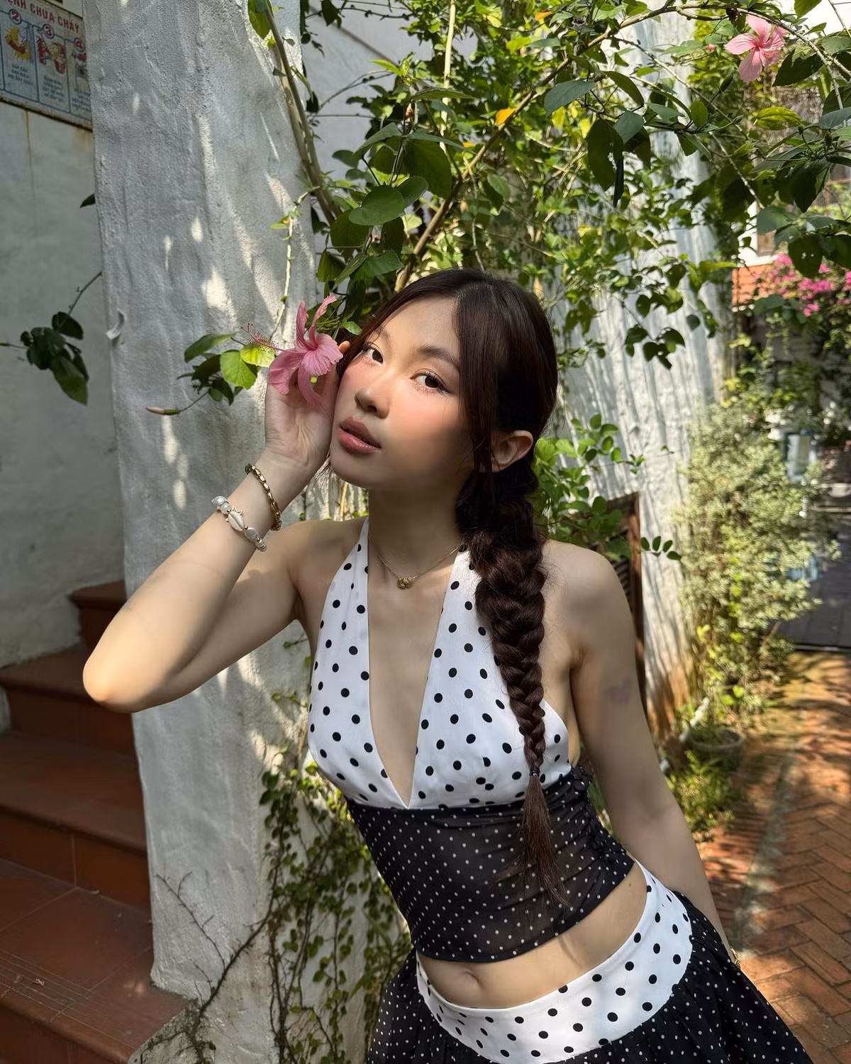 Chất liệu vải voan mỏng nhẹ tạo độ bay bổng, mềm mại khi di chuyển, khiến từng bước đi của cô nàng thêm phần uyển chuyển và tự nhiên. Chân váy ngắn xòe với hai lớp vải xen kẽ màu sắc và họa tiết chấm bi nhỏ tinh tế, vừa mang lại sự trẻ trung, vừa giúp tạo hiệu ứng đôi chân dài và thon hơn.