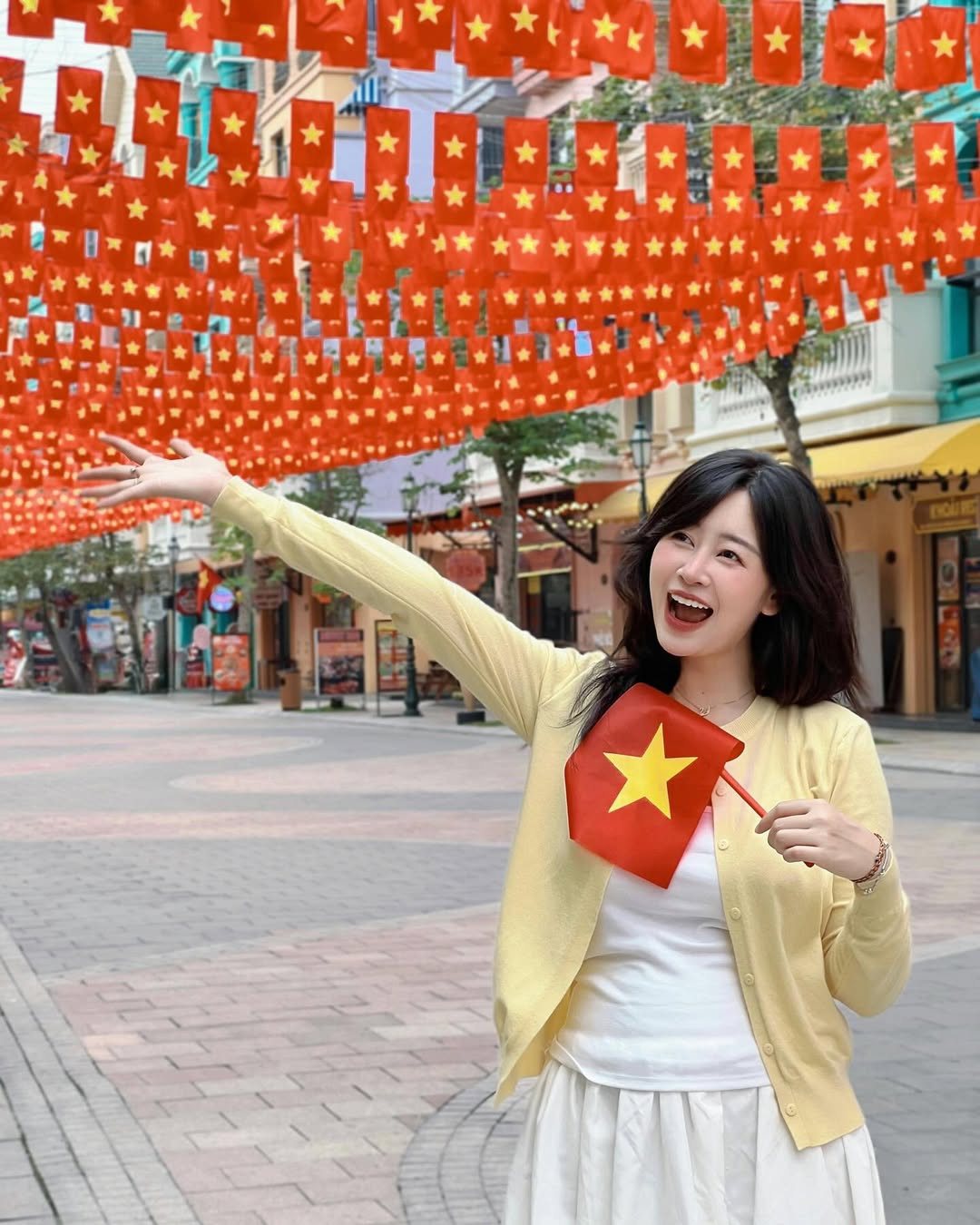 Phụ kiện được tiết chế tối giản, chỉ cần một lá cờ nhỏ trên tay cùng biểu cảm tự nhiên, cô nàng đã có loạt khoảnh khắc sống động và đậm chất lễ hội.