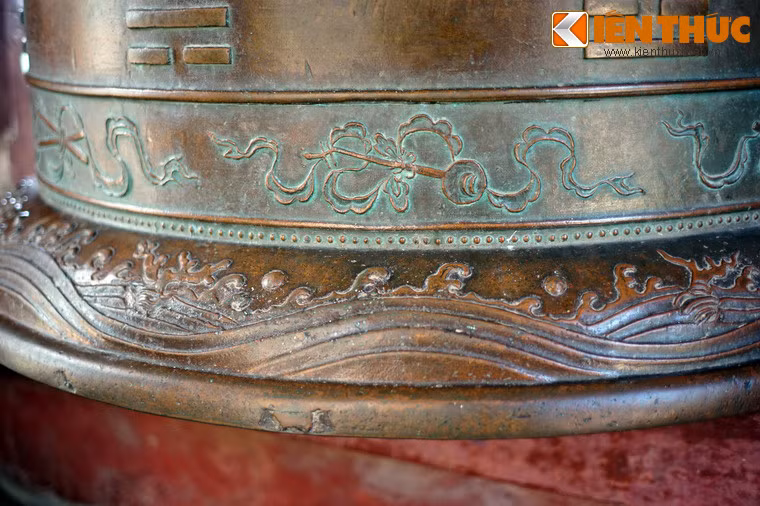 Phía dưới là các hình chạm nổi trong bộ bát bửu, chạy quanh sát vành miệng chuông, được bố trí ở khoảng trống xen kẽ với 8 biểu tượng của bát quái ở phía trên, lần lượt là: gươm, đèn lồng, ống sáo, đàn nguyệt, hai cây bút lông, bầu rượu, phách, quạt vả.
