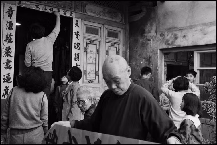 Nhà thư pháp và các thanh viên gia đình trang hoàng nhà cửa bằng các câu đối đỏ trong dịp Tết Nguyên Đán ở Đài Trung. Ảnh: Patrick Zachmann/ Magnum Photos.