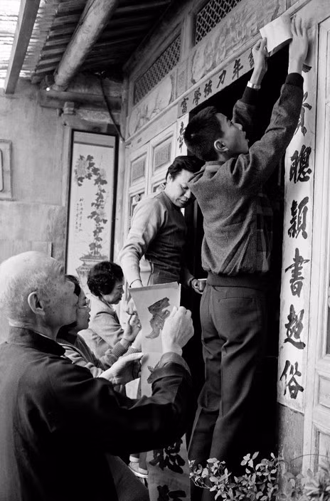 Nhà thư pháp và các thành viên gia đình trang hoàng nhà cửa bằng các câu đối đỏ trong dịp Tết Nguyên Đán ở Đài Trung. Ảnh: Patrick Zachmann/ Magnum Photos.