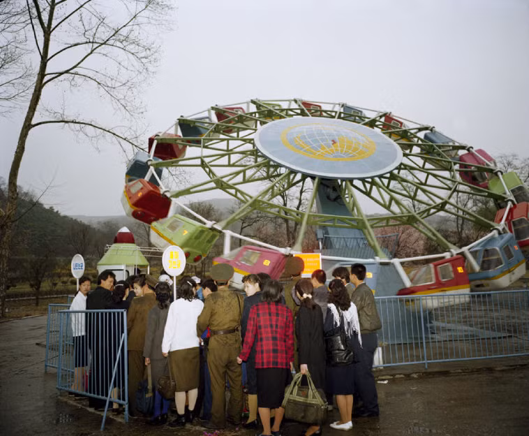 Người dân Bình Nhưỡng xếp hàng trước trò chơi đu quay ở khu vui chơi Mong Yordea. Ảnh: Martin Parr/ Magnum Photos.
