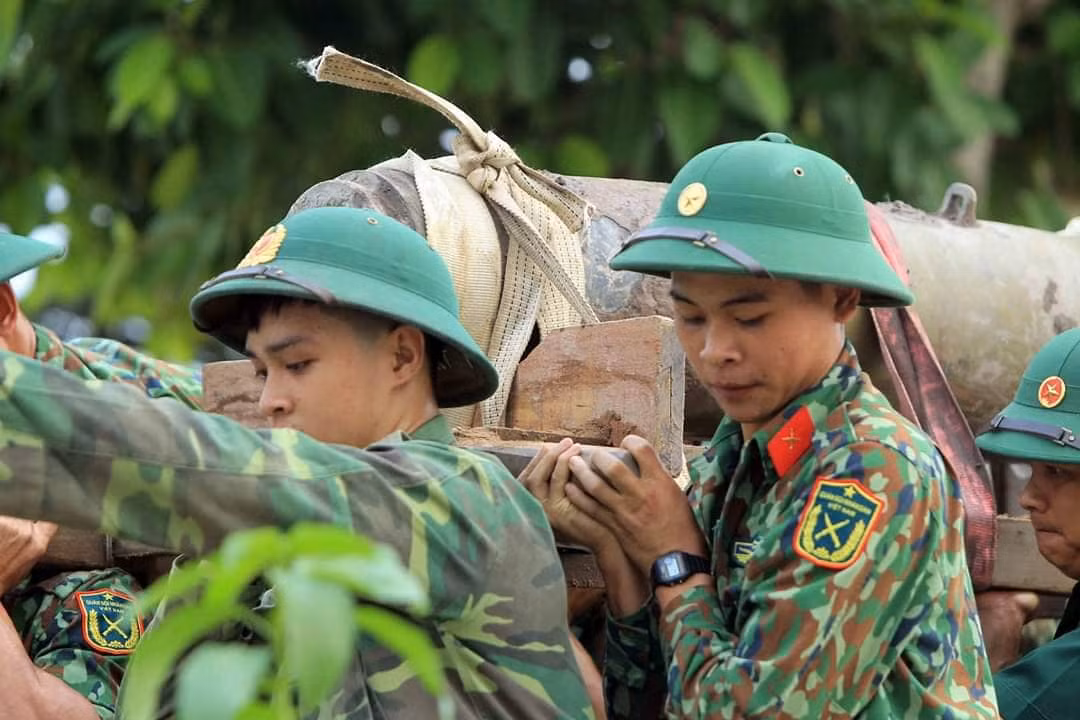 Lực lượng công binh khiêng quả bom từ vị trí dưới mép sông Tam Bạc.