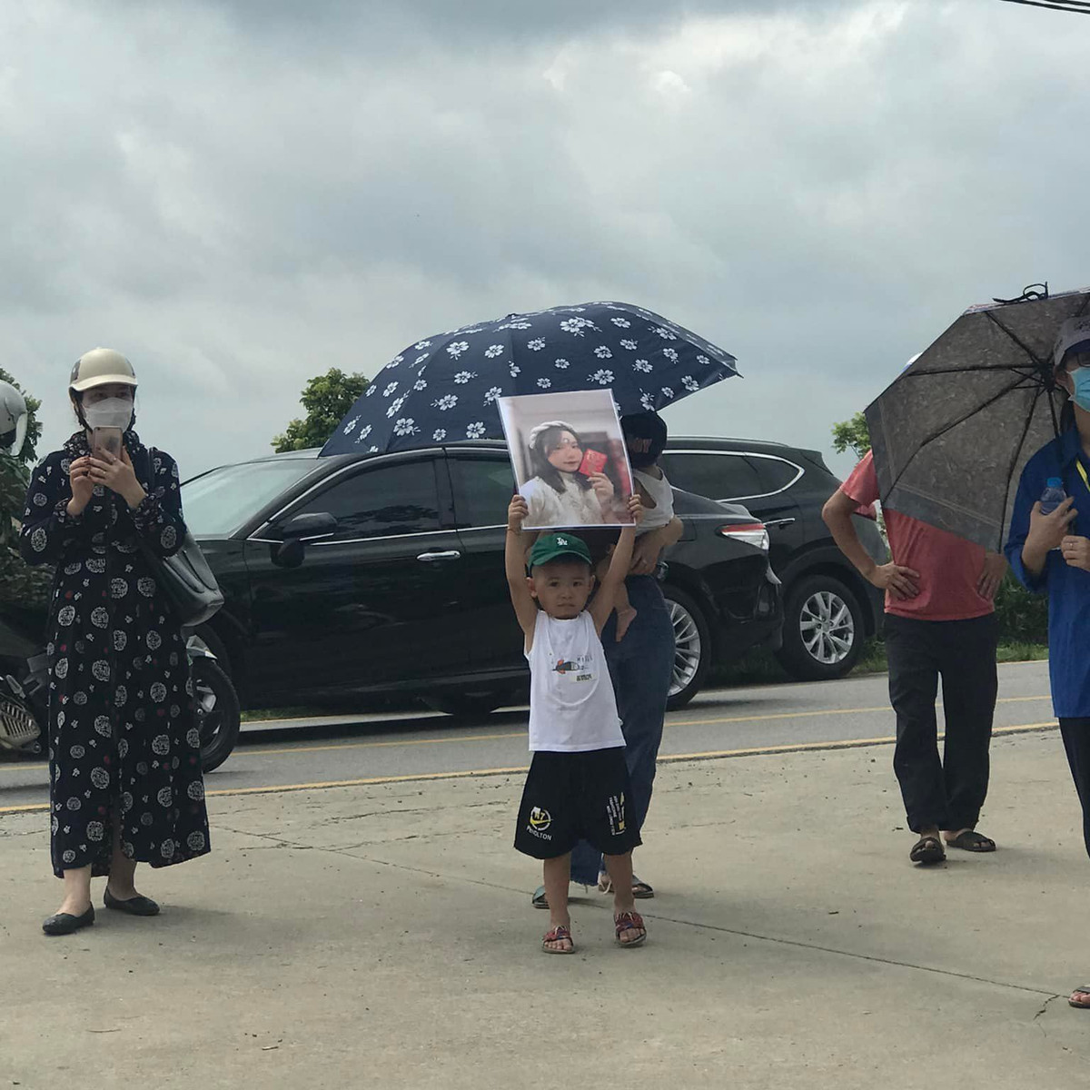 Ấn tượng nhất có lẽ là hình ảnh một bé trai đứng trước cổng điểm thi tốt nghiệp cổ vũ chị gái. Đáng chú ý cậu bé còn ôm tấm ảnh của chị để cổ vũ.