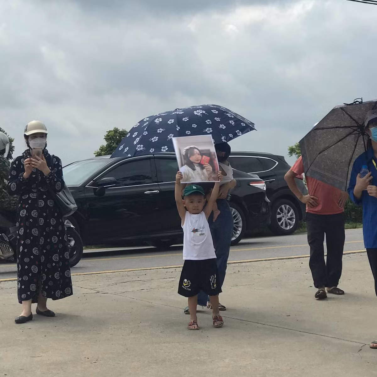 Ấn tượng nhất có lẽ là hình ảnh một bé trai đứng trước cổng điểm thi tốt nghiệp cổ vũ chị gái. Đáng chú ý cậu bé còn ôm tấm ảnh của chị để cổ vũ.