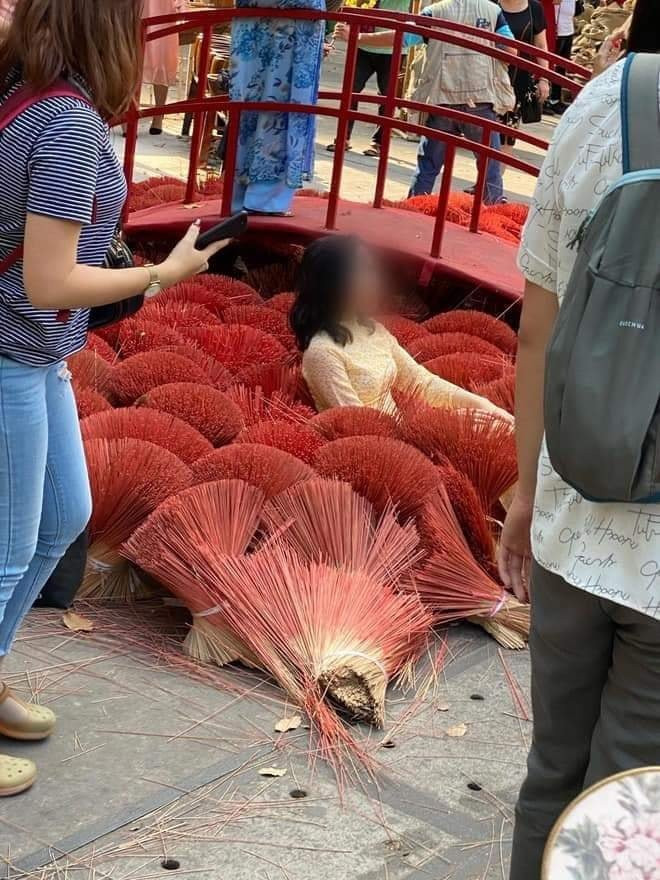 Theo những hình ảnh được đăng tải, một khoảng sân được xếp nhiều bó hương đỏ đẹp mắt để trang trí, tuy nhiên, điều đáng nói là có 2 người phụ nữ mặc áo dài, thoải mái nằm đè thẳng xuống những bó hương rồi tươi cười tạo dáng để chụp ảnh khiến nhiều người nóng mắt.