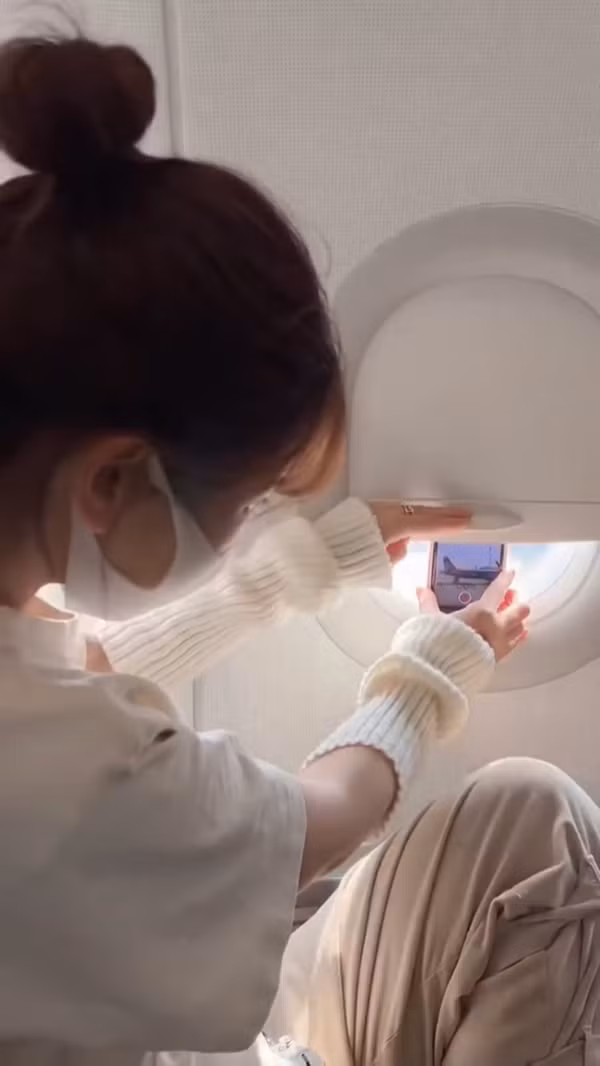 Nàng hot girl TikTok nổi tiếng đã kéo tấm che cửa sổ xuống để giữ cho điện thoại không rơi trong lúc đang “săn mây” khi máy bay đang cất cánh.