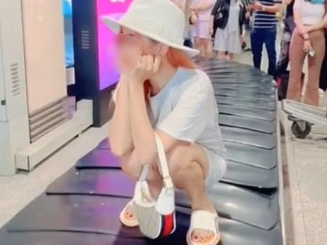 Cụ thể, cô gái này đã ngồi hẳn lên băng chuyền hành lý khi nó vẫn đang hoạt động, xung quanh là nhiều hành động đang đứng chờ lấy hành lý.