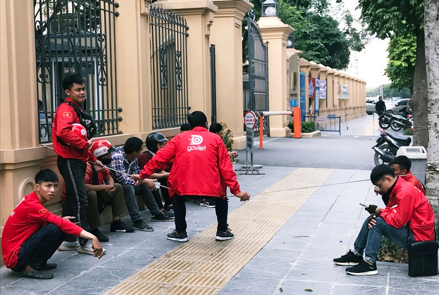 Một nhóm tài xế khác thì ngồi la liệt trên vỉa hè, đối diện với trụ sở Công ty Go-Viet tại Hà Nội.