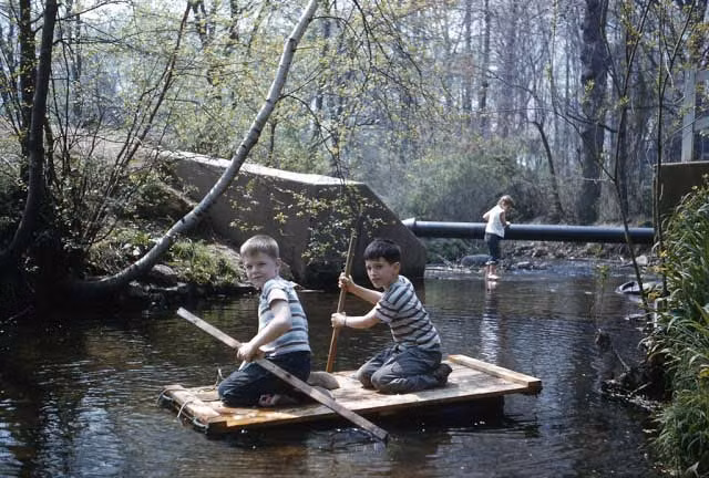 Hai bé trai thích thú chèo ván thuyền trên con suối nhỏ. Ảnh VT
