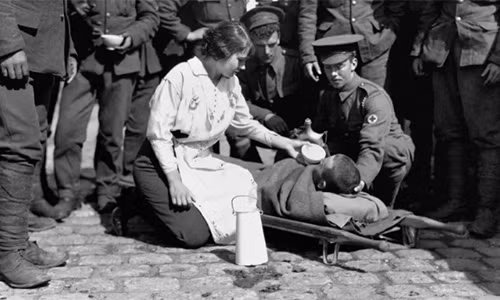 Một người lính Anh bị thương được mọi người chăm sóc vết thương và cho uống nước. Ảnh chụp tại Pháp năm 1916.