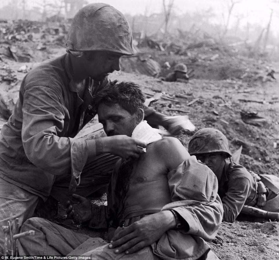 Một quân y Mỹ băng bó vết thương cho một binh sĩ bị thương ở cổ. Bức ảnh này được chụp tại Tanapag, Saipan tháng 6/1944.