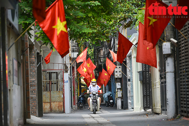 Người dân treo cờ Tổ quốc đỏ rực trên nhiều tuyến phố và ngõ ngách. (Ảnh Tin tức)