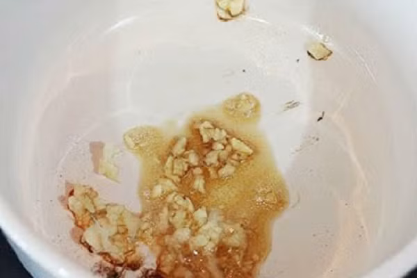 Cho nồi lên bếp, để nóng. Đun lửa nhỏ vừa cho dầu vào rồi phi tỏi vàng dậy mùi thơm nức. (Ảnh:toinayangi.com)