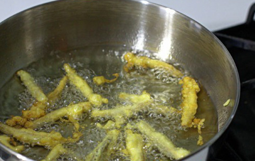 Trộn hỗn hợp nước sốt gồm: nước tương + đường + ớt rồi cho vào chảo đun sôi. Thả phần hoa chuối đã chiên vào đảo đều cho gia vị áo đều từng chiếc hoa chuối chiên rồi rưới thêm chút dầu ăn. Ảnh: bepgiadinh