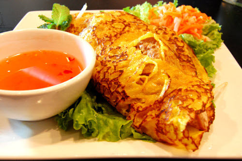 Khi nguyên liệu chín hẳn, gấp bánh làm đôi và xúc ra đĩa. Bánh ăn cùng nước mắm chanh tỏi ớt và rau sống (cải bẹ xanh, xà lách, đọt bằng lăng, đọt bứa, rau thơm, dưa leo…). Ảnh: loca