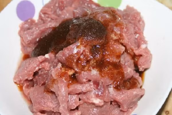 Trước khi thực hiện món ăn này, thịt trâu được thái mỏng ngang thớ, ướp cùng với 1 thìa nước tương, chút tiêu, tỏi bằm, dầu ăn, gia vị và 1 thìa bột ngô chừng 15 phút cho ngấm đều. (Ảnh: phununet.com)