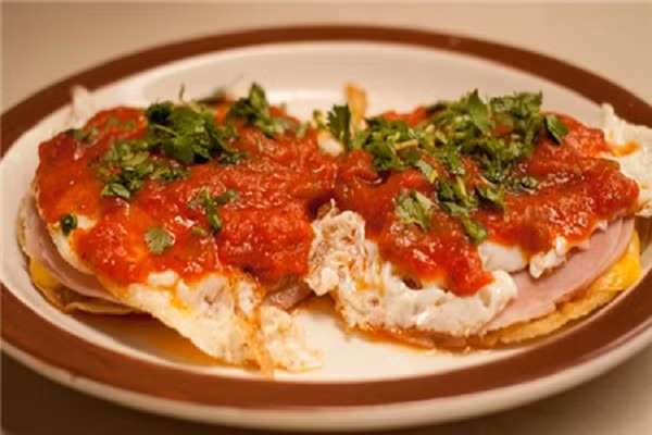 Trứng ốp la bánh bắp (Huevos rancheros) của Mexico. Đây là một món ăn sáng rất phổ biến ở xứ sở của chiếc mũ sombrero, trong đó bao gồm trứng rán được bày lên trên một chiếc bánh kếp bột bắp, bên trên rưới nước xốt cà chua ớt, phô mai, dầu ô liu trông vô cùng thơm ngon và hấp dẫn.