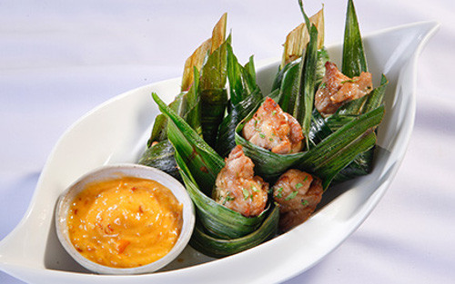 Sau khi gà đã thấm gia vị, lấy từng miếng là dứa gói miếng thịt gà lại. Cho gà vào chiên. Khi lá dứa vàng giòn là gà chín. Món ăn dùng nóng với muối tiêu chanh. Ảnh: monngonmoingay.