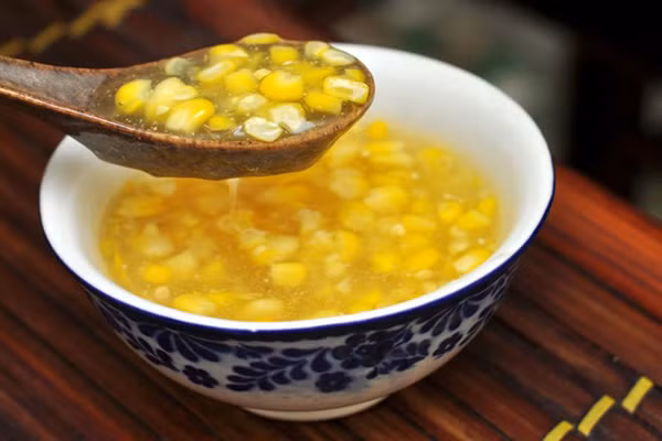 Bưng chén chè trên tay, nhìn sắc màu vàng mơ tươi sáng của hạt bắp cồn, nhìn ngàn cờ bắp đang lay ngọn lá lao xao ngoài triền sông, cùng bạn bè vui đùa trò chuyện, lại thưởng thức vị thơm dẻo ngọt quyến rũ, ăn một lại muốn hai. Nấu chè bắp là bí quyết riêng của người cồn Hến nên chè ở đây có phong vị riêng mà không nơi nào khác có được. (Ảnh: Vannghe).