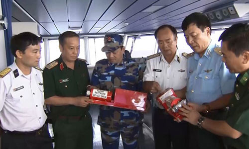 Phó đô đốc Phạm Ngọc Minh (thức ba từ phải sang) và Thiếu tướng Nguyễn Hữu Chí (thứ hai từ phải sang) cùng các cán bộ Sở Chỉ huy trên tàu Cảnh sát biển 8002 xem xét hộp đen vừa được tìm thấy.