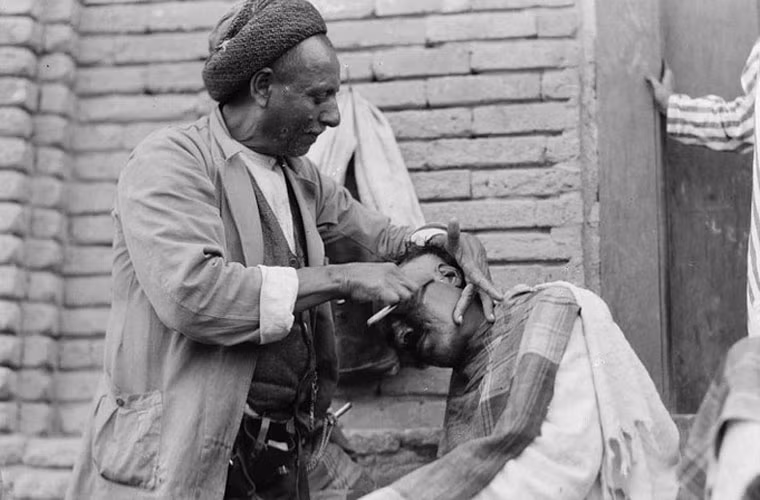 Người thợ cắt tóc dạo trên một con phố ở Baghdad.