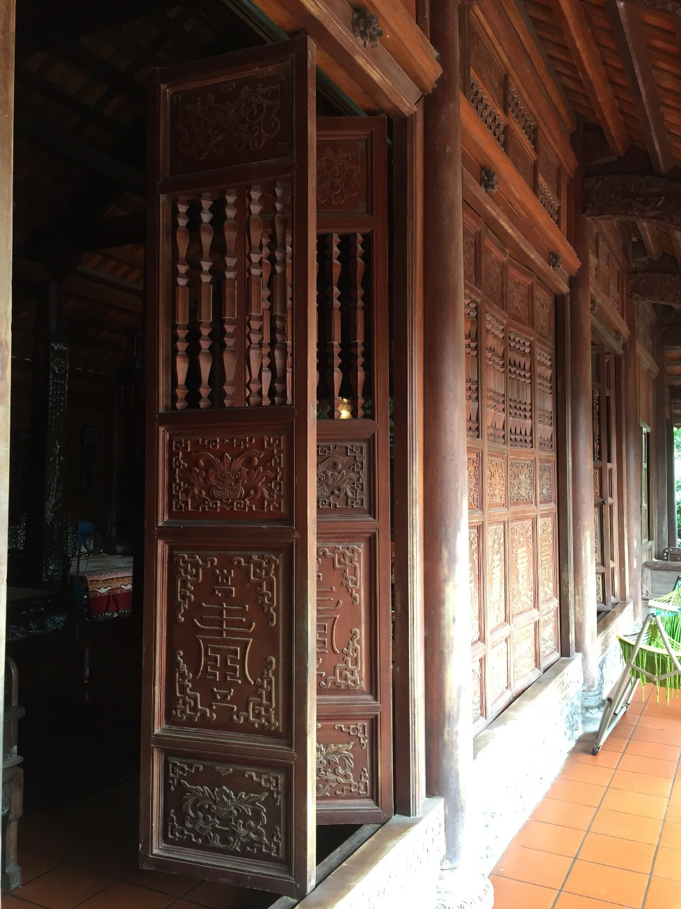 Phần cửa phía trước của ngôi nhà gỗ “khủng”. Các cánh cửa đều được điêu khắc hoa văn, hoa lá, chim muông. Gia chủ còn cầu kỳ đặt thợ ở Thanh Hoá xẻ đá làm một cái nền toàn bằng đá xanh, cao chừng 1,5m, trên đó có 9 bậc. Một tốp thợ cỡ chục người làm cật lực gần nửa tháng mới ráp những tảng đá xẻ lớn vào nhau và khít đến độ không có kẽ nào con kiến, con mối có thể chui lọt.