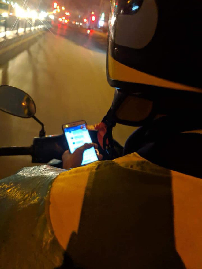 Tài xế xe ôm vừa lái xe vừa lướt facebook.