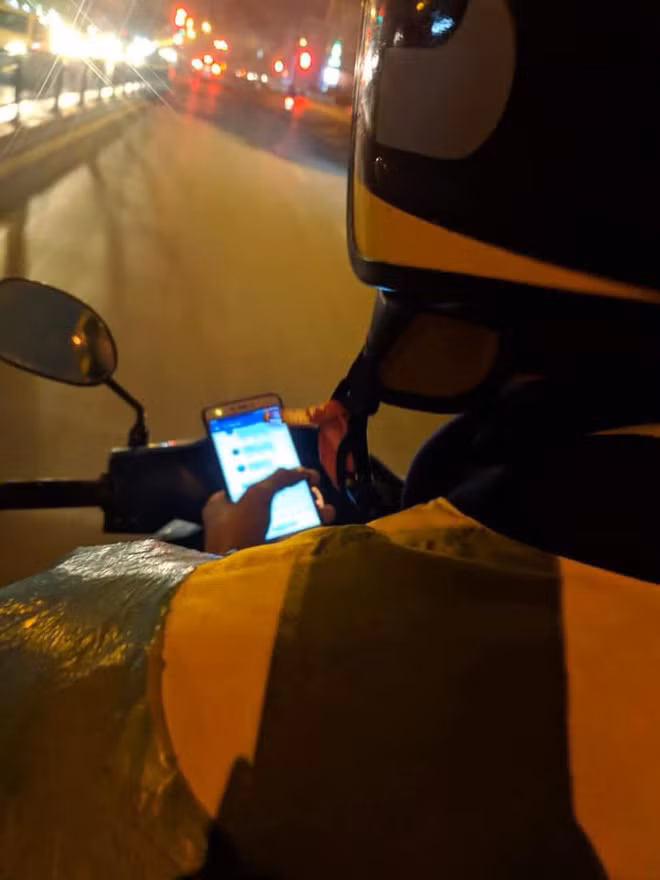 Tài xế xe ôm vừa lái xe vừa lướt facebook.