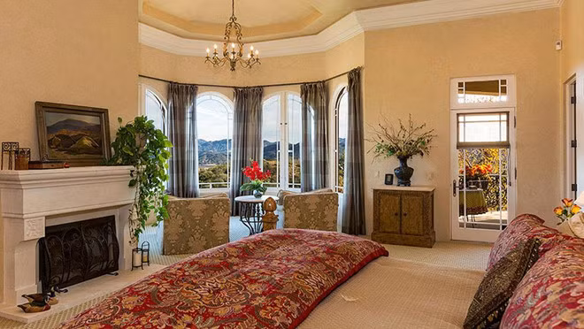 Phòng ngủ chính rộng lớn với lò sưởi, khu vực tiếp khách và những ô cửa kính giúp không gian ngập tràn ánh sáng tự nhiên.