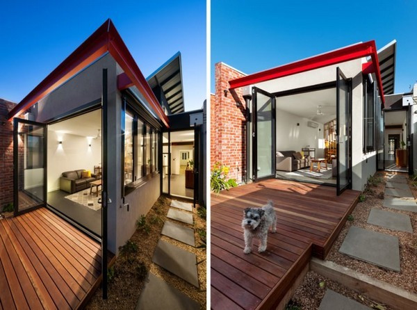 Phần hiên nhà ngoài trời được làm bằng các miếng gỗ ghép cùng với một lối đi trải đầy sỏi bên hông dẫn ra khu vườn tăng thêm sự tươi mát, gần gũi với thiên nhiên của ngôi nhà. Trong khi đó các bức tường ngoài sân lại được làm bằng gạch đỏ tái chế đem lại cảm giác ấm áp cho gia chủ.