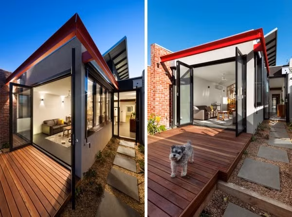 Phần hiên nhà ngoài trời được làm bằng các miếng gỗ ghép cùng với một lối đi trải đầy sỏi bên hông dẫn ra khu vườn tăng thêm sự tươi mát, gần gũi với thiên nhiên của ngôi nhà. Trong khi đó các bức tường ngoài sân lại được làm bằng gạch đỏ tái chế đem lại cảm giác ấm áp cho gia chủ.