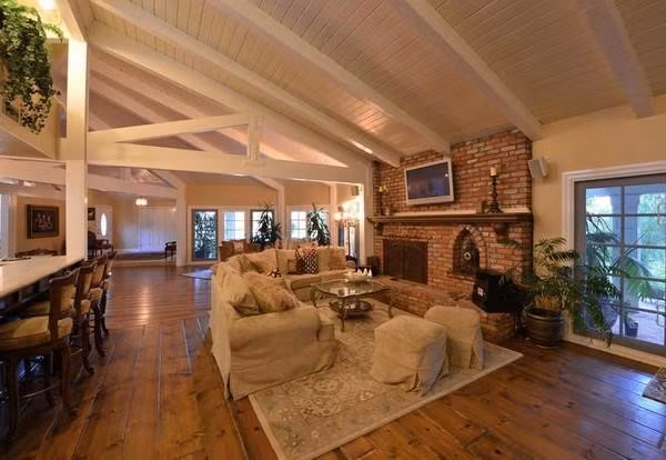 Phòng khách rộng lớn với bộ sofa, lò sưởi gạch, cùng những cánh cửa ra vào mang phong cách Pháp.