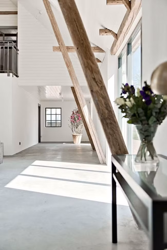 Sàn bê tông bóng và các xà gỗ ở trần bổ sung cho tường nhà và trần nhà màu trắng đưa đến sự đơn giản, tinh tế.