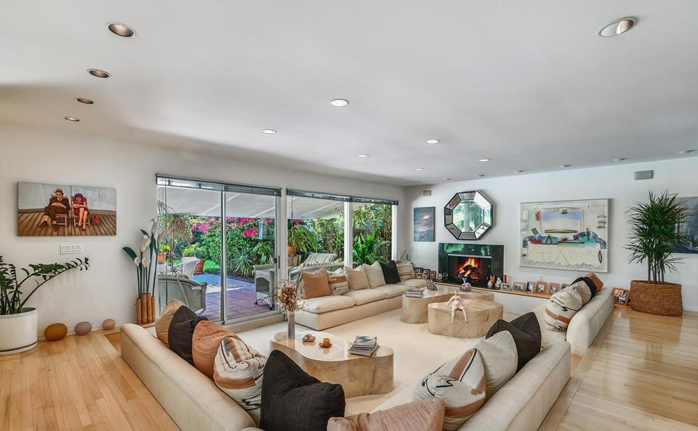 Phòng khách rộng rãi được thiết kế với lò sưởi cùng bộ sofa chìm. Những cánh cửa to lớn dẫn ra hiên nhà có mái che. Ảnh: Douglas Elliman.