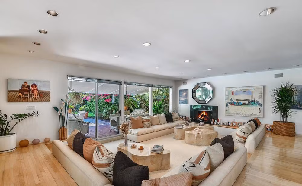 Phòng khách rộng rãi được thiết kế với lò sưởi cùng bộ sofa chìm. Những cánh cửa to lớn dẫn ra hiên nhà có mái che. Ảnh: Douglas Elliman.