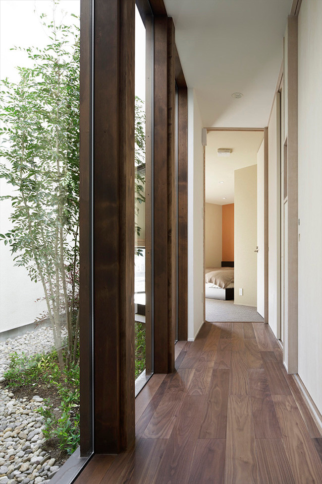 Đồ gỗ được sử dụng nhằm tăng tính thẩm mỹ và hiện đại. Bức tường lớn che khuất phần cửa chính lùi vào 45 độ, giúp giảm nhiệt lượng khi nắng chiếu trực tiếp vào mặt tiền. Không gian bên trong như được nối liền với thiên nhiên cây xanh bên ngoài.