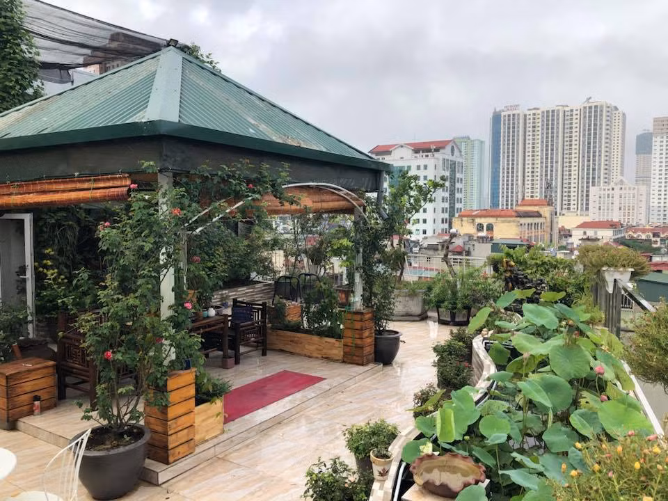 Giữa sân thượng, chị Thúy chủ thiết kế mái che đặt một bộ bàn ghế để mọi người vừa ngồi ngắm cảnh vừa thưởng trà trong mọi thời tiết. Còn gì tuyệt vời hơn khi vừa nhâm lý tách trà nóng vừa ngắm nhìn vẻ đẹp của một góc nhỏ Hà Nội từ trên cao.
