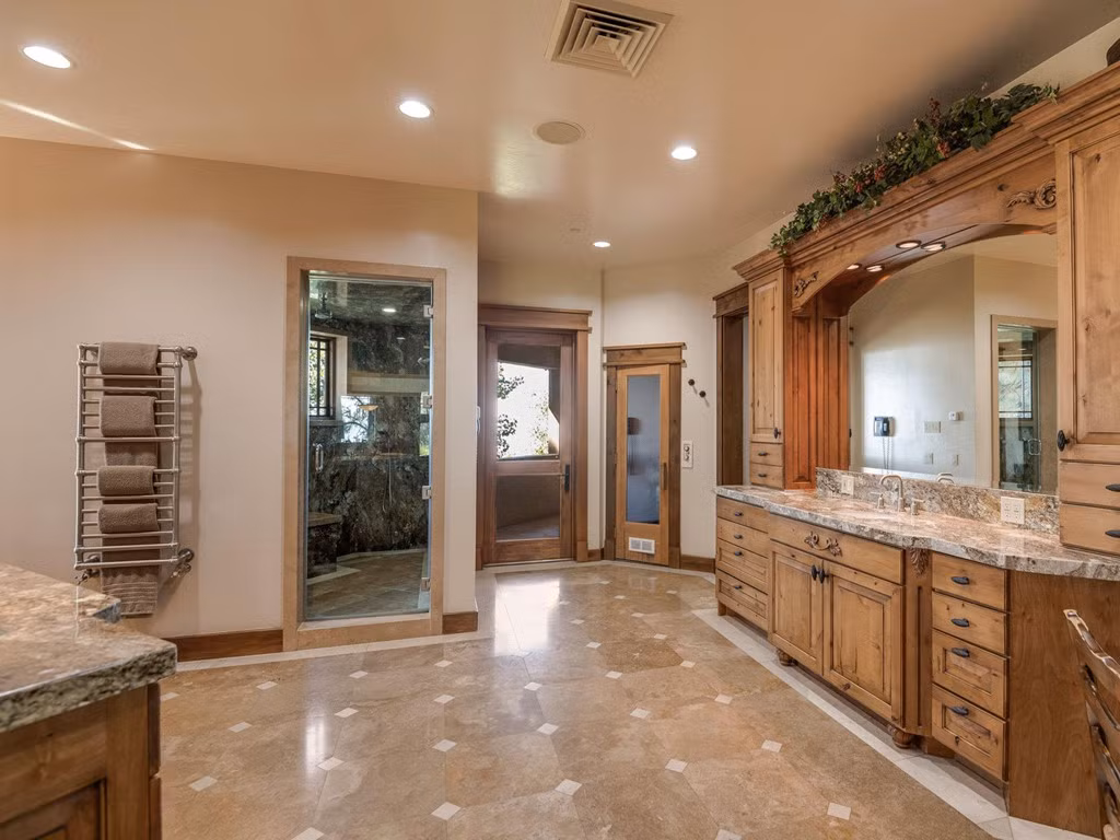 Các chi tiết trong phòng tắm hầu hết được ốp đá nâu, cùng ngôn ngữ thiết kế màu chung trong toàn bộ không gian nhà. Bên cạnh những ô cửa sổ đón ánh sáng tự nhiên từ ngoài và tạo cảm giác thư giãn, tấm gương lớn đặt chính giữa giúp không gian thêm sâu rộng.