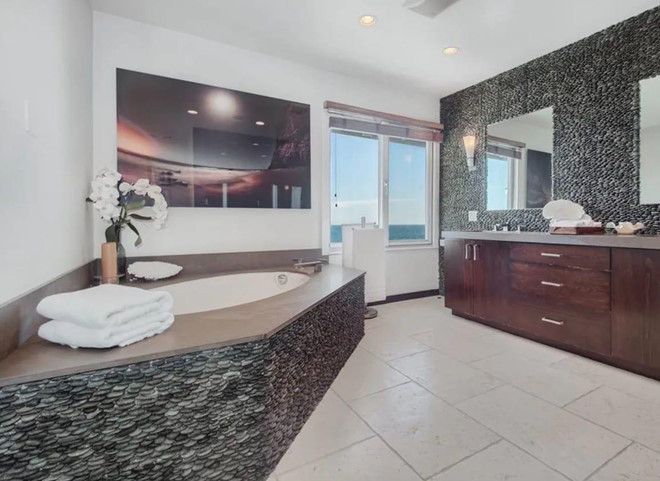 Phòng tắm chính xa hoa được trang bị đầy đủ với đa dạng các khu vực riêng biệt. Đồ nội thất là sự kết hợp giữa gỗ và đá đen.