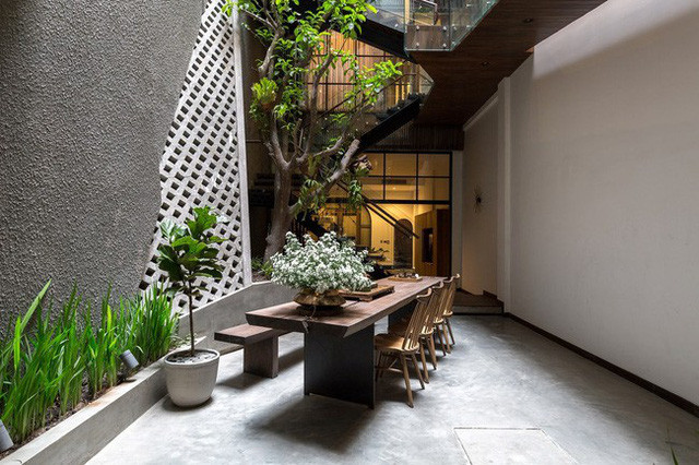 Một điểm thú vị phải kể đến trong ngôi nhà này chính là khoảng sân vườn ở giữa nhà. Thực ra ngày càng có nhiều ngôi nhà ống áp dụng sân kiêm giếng trời ở giữa nhà như một giải pháp lấy sáng, thoáng cho tổng thể. Nhưng "chơi lớn" bớt khoảng diện tích sân vườn lớn thế này thì không nhiều. Tất nhiên cái gì cũng có cái giá của nó, cái giá của sự hi sinh cho sân vườn là sự thoáng đãng cho toàn bộ ngôi nhà. Nhờ nó mà phòng khách, sân vườn đều có sự thông thoáng tuyệt vời. Hơn thế nữa, khoảng sân này vừa đủ rộng để trồng cây, rồi bố trí bàn ăn - góc thưởng trà dưới gốc cây, mang đến cho gia chủ cảm giác về mái nhà thời thơ ấu, yên bình dưới tán cây xanh.