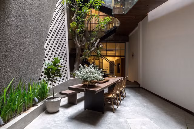 Một điểm thú vị phải kể đến trong ngôi nhà này chính là khoảng sân vườn ở giữa nhà. Thực ra ngày càng có nhiều ngôi nhà ống áp dụng sân kiêm giếng trời ở giữa nhà như một giải pháp lấy sáng, thoáng cho tổng thể. Nhưng "chơi lớn" bớt khoảng diện tích sân vườn lớn thế này thì không nhiều. Tất nhiên cái gì cũng có cái giá của nó, cái giá của sự hi sinh cho sân vườn là sự thoáng đãng cho toàn bộ ngôi nhà. Nhờ nó mà phòng khách, sân vườn đều có sự thông thoáng tuyệt vời. Hơn thế nữa, khoảng sân này vừa đủ rộng để trồng cây, rồi bố trí bàn ăn - góc thưởng trà dưới gốc cây, mang đến cho gia chủ cảm giác về mái nhà thời thơ ấu, yên bình dưới tán cây xanh.