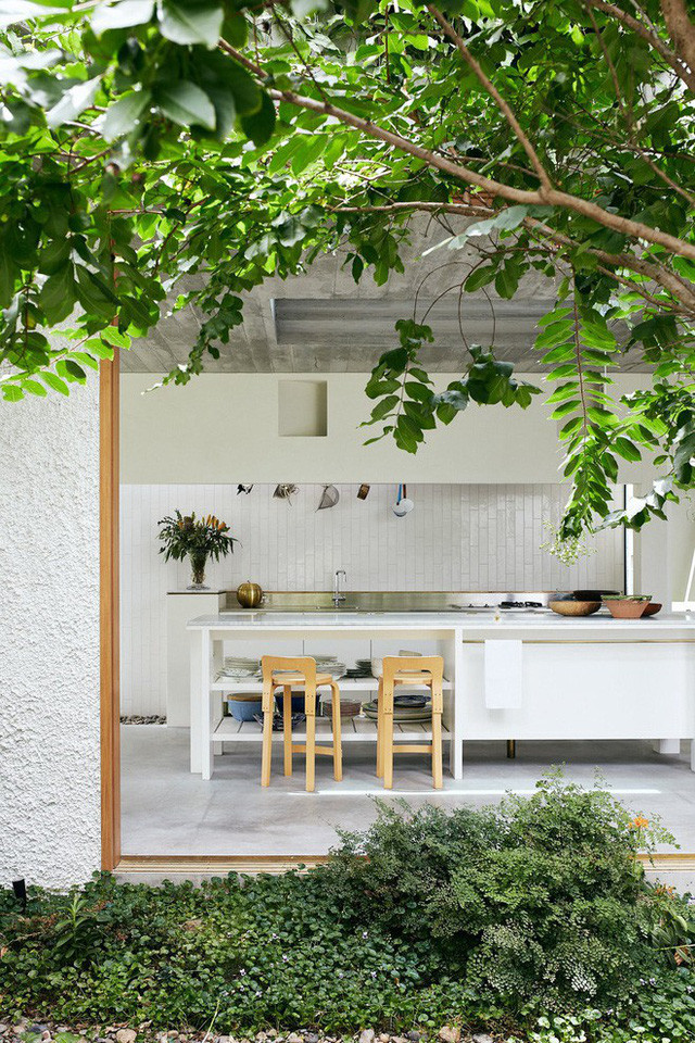 Cây xanh luôn tạo ra những khoảng trong lành, mát dịu, đặc biệt là trong những ngày hè nóng nực. Góc nhỏ ngồi trò chuyện, tiếp khách được thiết kế khá ấn tượng với ghế gỗ thêm nệm màu hường. Phong cách Địa Trung Hải được nhấn mạnh với sàn bê tông và họa tiết trên thảm, tranh treo tường với màu sắc sống động.