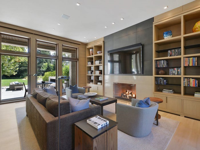 Phòng khách thoáng đãng, sang trọng với tông màu be chủ đạo cùng nội thất bằng gỗ xung quanh. Điểm đặc biệt của căn phòng là một chiếc lò sưởi bằng đá vôi và các kệ sách được thiết kế âm tường.