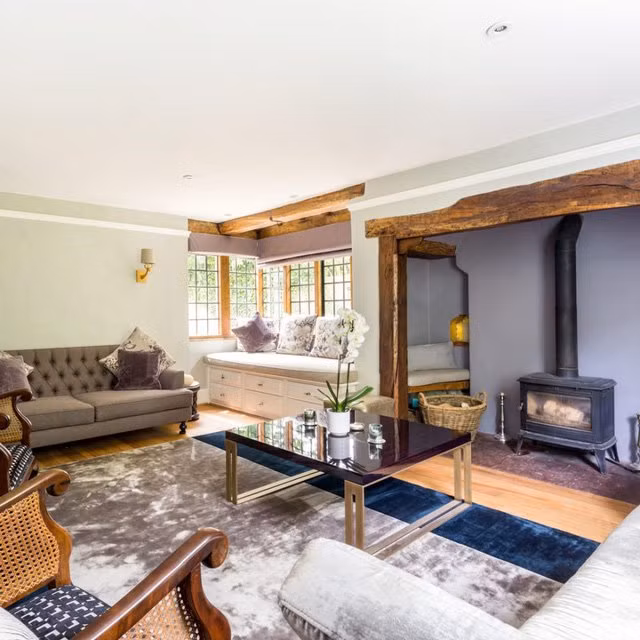 Phòng khách được tăng thêm sang trọng bằng tấm thảm lụa lớn cùng ghế sofa và đệm nhung. Chủ nhà vẫn giữ lại các lò đốt gỗ và dầm gỗ của căn nhà cũ để tưởng niệm.