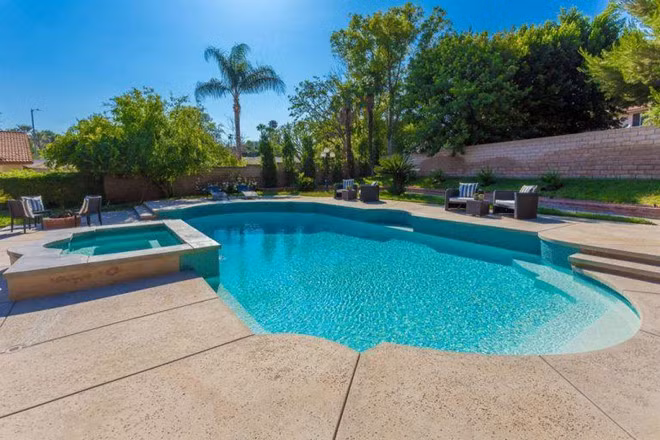 Hồ bơi và bồn tắm nước nóng ngoài trời được bao quanh bởi các bức tường và hàng cây cao nhằm đảm bảo tính riêng tư cho gia chủ.