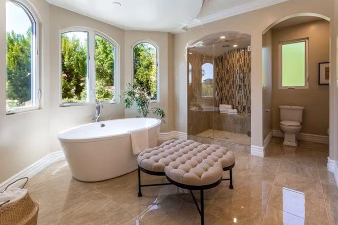 Phòng tắm chính được lát đá cẩm thạch và chia thành nhiều khu vực khác nhau. Những ô cửa sổ bao quanh giúp không gian nơi đây trở nên thoáng đãng.