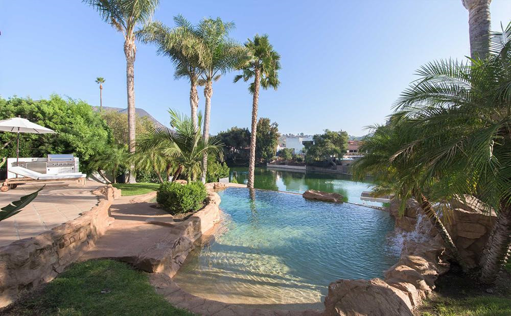 Hồ bơi và bồn tắm nước nóng ngoài trời được thiết kế độc đáo, thân thiện với thiên nhiên cùng hàng cọ bao quanh mang đậm nét đặc trưng của California. Ngay phía dưới là một hồ nhân tạo rộng hơn 24.000 m2 nơi gia chủ cùng hàng xóm có thể giải trí bằng môn chèo thuyền kayak.